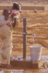 Water: foto van een vrouw die een emmer met water vult bij pomp